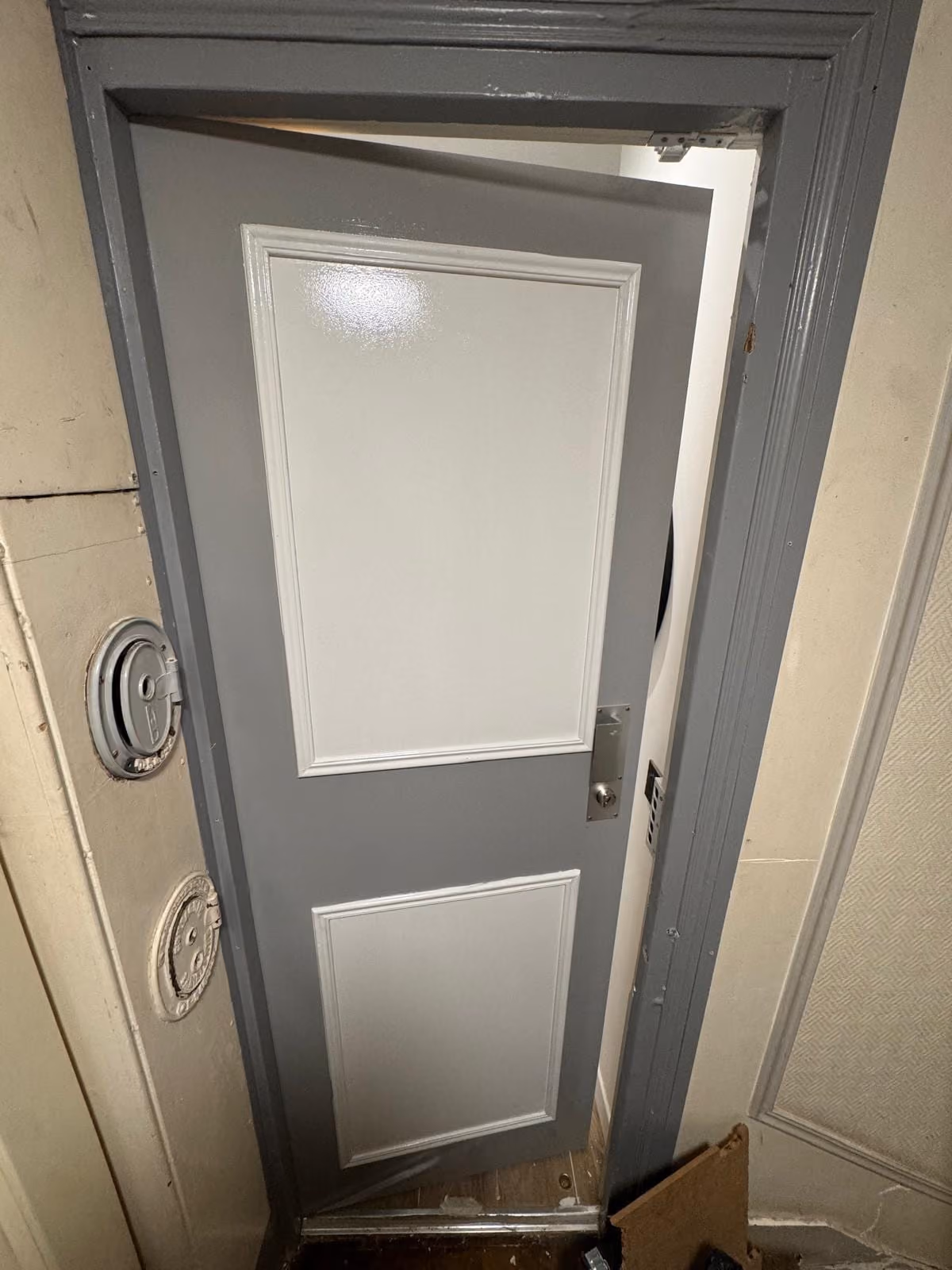 Porte palière grise avec serrure posée dans immeuble ancien